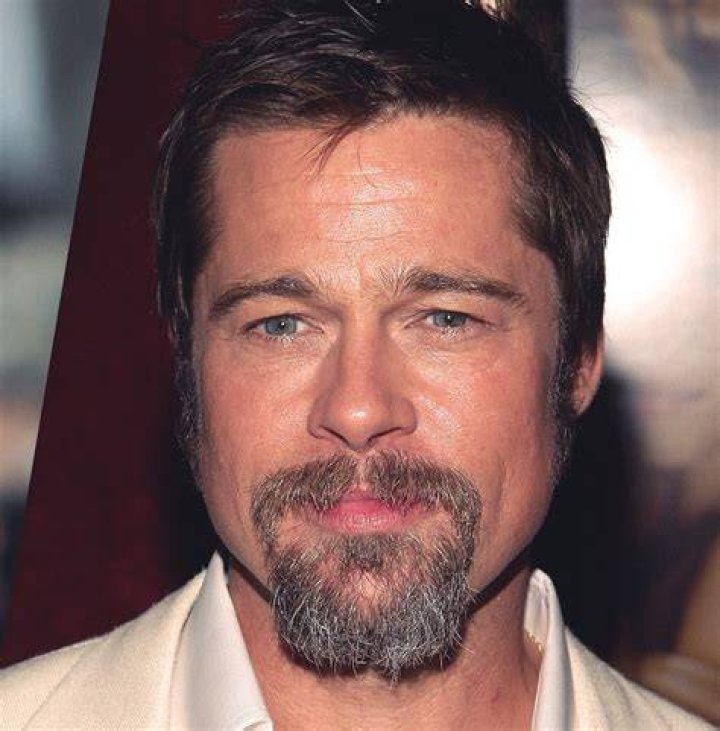 a man with a goatee and beard wearing a leather jacket looking at the