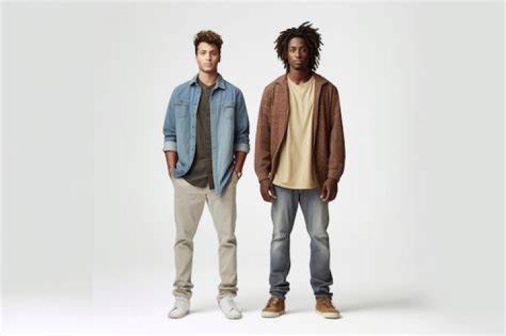 two men standing next to each other in front of a yellow wall with